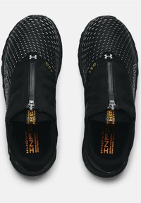 Czarne sportowe buty wsuwane z teksturowaną siateczkową cholewką, zamkiem błyskawicznym oraz markowymi akcentami w żółtym i pomarańczowym kolorze na wkładkach.