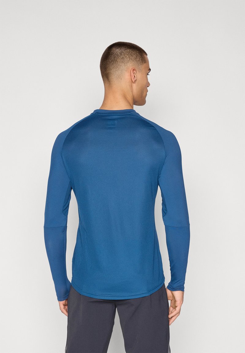 Camisa de manga larga en azul oscuro, fabricada con un tejido ligero y transpirable, con un patrón texturizado y un acabado suave, presenta mangas raglán.