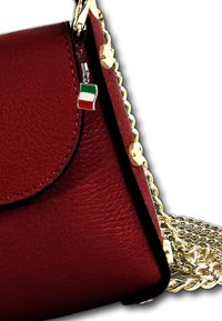 Rode leren handtas met gouden hardware, voorzien van een kettingband en een klein Italiaans vlaggetje charm dat aan de rits is bevestigd. Gestructureerde oppervlakte.