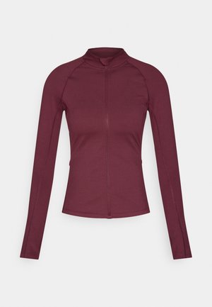 Ilgas rankovėmis, užtrauktuku užsegamas viršus bordo spalvos, pagamintas iš lygaus, tamprios medžiagos. Turi raglano tipo rankoves ir aukštą apykaklę.