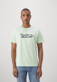 Gaiši zaļa kokvilnas T-kreklu ar apaļu kakla izgriezumu un īsām piedurknēm, uz krūtīm ar melnu "Pepe Jeans" logo.