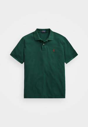 Grønn poloskjorte laget av teksturert bomull med kragehals, to knapper, og en liten rød logo brodert på venstre bryst.