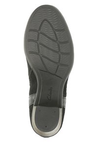 Musta Clarks -kenkä, jonka pohja on varustettu tekstuurilla ja liukkaammalla kantapäähdellä, kuvattuna pohjasta.