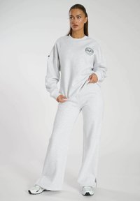 Grijze sweatshirt en joggingsbroek set van zachte stof, met een ronde logo op de borst, een relaxed fit en een lichte flare in de broek.