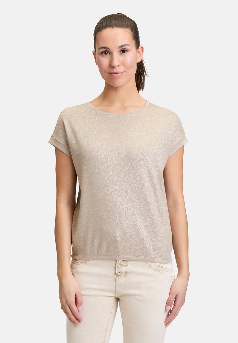 Metallic gold T-Shirt mit kurzen Ärmeln, rundem Halsausschnitt, lässiger Passform und weicher Textur, kombiniert mit hellen, eng anliegenden Hosen.