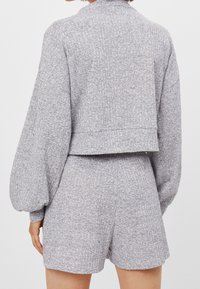 Woman wearing a light gray textured long-sleeve cropped top with matching high-waisted shorts, shown from the back.