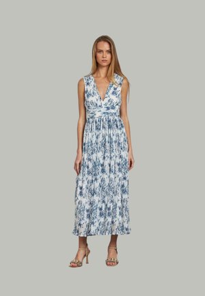 Blaues und weißes Blumenkleid im Maxi-Stil mit tiefem V-Ausschnitt und plissiertem Rock. Getragen mit goldenen Absätzen, aus einem fließenden, leichten Stoff.