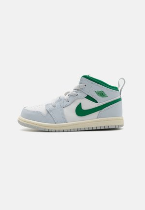 Nike puszābju sporta apavi baltā ādas krāsā ar zaļiem akcentiem. Iekļauj teksturētu zoli, mīkstinātu apkakli un auklu slēgšanu.