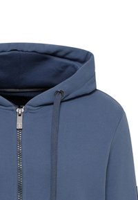 Blue zip-up hoodie featuring a drawstring hood, flatlock seams, and silver-tone zipper with textured fabric. Smooth texture and no visible patterns.