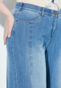 Jeans de mezclilla azul claro con un corte relajado, forma de pierna recta y un ligero desvanecimiento. Incluyen bolsillos delanteros y traseros con detalles de costura.