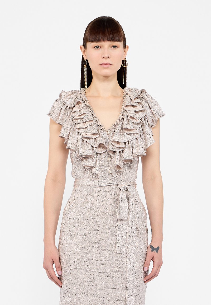 Blouse froncée en tissu métallique léger, avec un profond décolleté en V et des détails de boutons, accompagnée d'une ceinture nouée assortie à la taille.