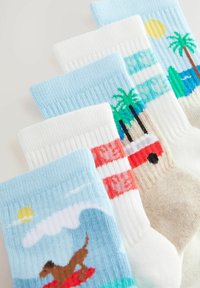 Set of four socks. Light blue and white ribbed knit, featuring patterns of a dog on a surfboard, palm trees, beaches, and sun.