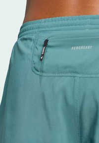 AEROREADY løpeshorts i teal, med elastisk midjebånd, baklomme med svart glidelås og glatte, lette stoffer.