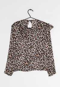 Blusa con stampa leopardata, scollo arricciato, pattern in nero, beige e arancione, maniche lunghe e dettagli sulla schiena scoperta, su una gruccia nera.