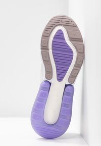 Suela de zapatilla con una combinación de colores blanca y morada, que presenta patrones de goma texturizados y un destacado logo de Nike en el talón.