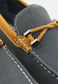 Zapatos de barco azul y amarillo con un diseño perforado, acentos de cuero, herrajes de metal y detalles de costura en contraste.