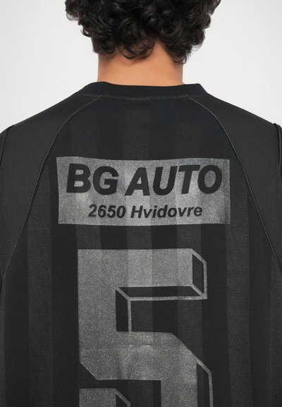 Črn športni dres z teksturiranim dizajnom. "BG AUTO" in "2650 Hvidovre" natisnjeno v srebrni barvi, z velikim stiliziranim številom "5."