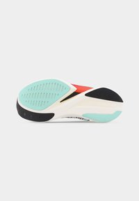 Σόλα αθλητικού παπουτσιού με λευκή, μαύρη και τιρκουάζ πέλμα, που εμφανίζει υφή με μοτίβα πρόσφυσης σε απλό ανοιχτό φόντο.