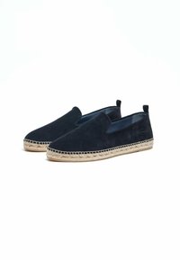 Chaussures en velours bleu marine à enfiler avec une semelle en jute d'espadrille, présentant un détail cousu le long du bord et sans matériel ni accents visibles.