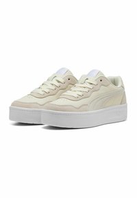 Baskets beiges au design lisse et texturé, dotées d'une semelle plateforme blanche, d'une fermeture à lacets et de subtils accents de logo sur le côté.
