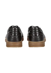 Zapatillas de cuero negras con parte superior texturizada y detalles acolchados, con una suela de goma marrón y el logo de la marca en el talón.