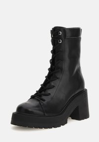 Stivale alla caviglia in pelle nera con tacco robusto, lacci frontali, cuciture in evidenza e suola in gomma testurizzata.