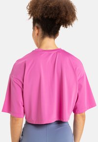 Top recortado de manga corta en una tela de color rosa brillante. Presenta un escote redondo y un corte holgado, con una textura suave y ligera. Se muestra la vista trasera.