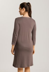 Brun knälång klänning med trekvartslånga ärmar, med spetsdetaljer vid ärmslut och en enkel rund halsringning. Slät tygtextur.