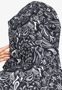 Schwarz gemusterte Kapuze mit komplexen weißen Paisley- und Blumenmotiven; glatte Stofftextur mit verstellbarem Kordelzug.