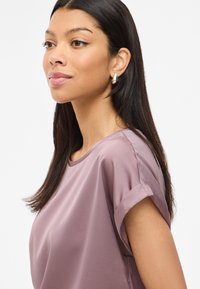 Light purple short-sleeve blouse with a round neckline and rolled cuffs in smooth fabric, featuring a subtle sheen and relaxed fit.