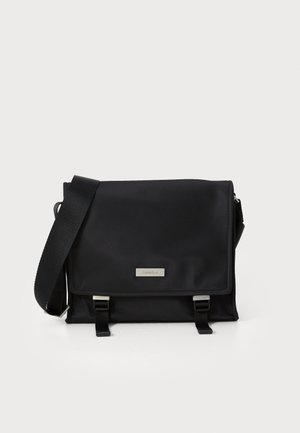 Borsa a tracolla nera realizzata in nylon liscio con chiusura a patta, hardware in argento e tracolla regolabile intrecciata. Caratterizzata da un'etichetta con logo e dettagli con fibbia.