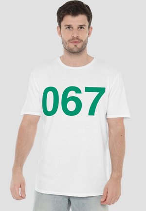 White cotton t-shirt featuring a large green numeral “067” printed in the center. Short sleeves and a crew neck design.