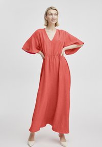 Maxikleid aus korallenfarbenem Stoff mit tiefem V-Ausschnitt, weiten Ärmeln und elastischem Bund. Mit seitlichen Schlitzen und fließendem Design. Schlichte Textur.