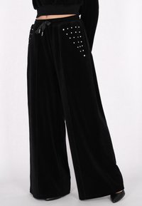 Czarne szyfonowe spodnie z szerokimi nogawkami, z elastycznym paskiem na sznurki oraz dekoracyjnymi srebrnymi ćwiekami ułożonymi w wzór na przednich kieszeniach.