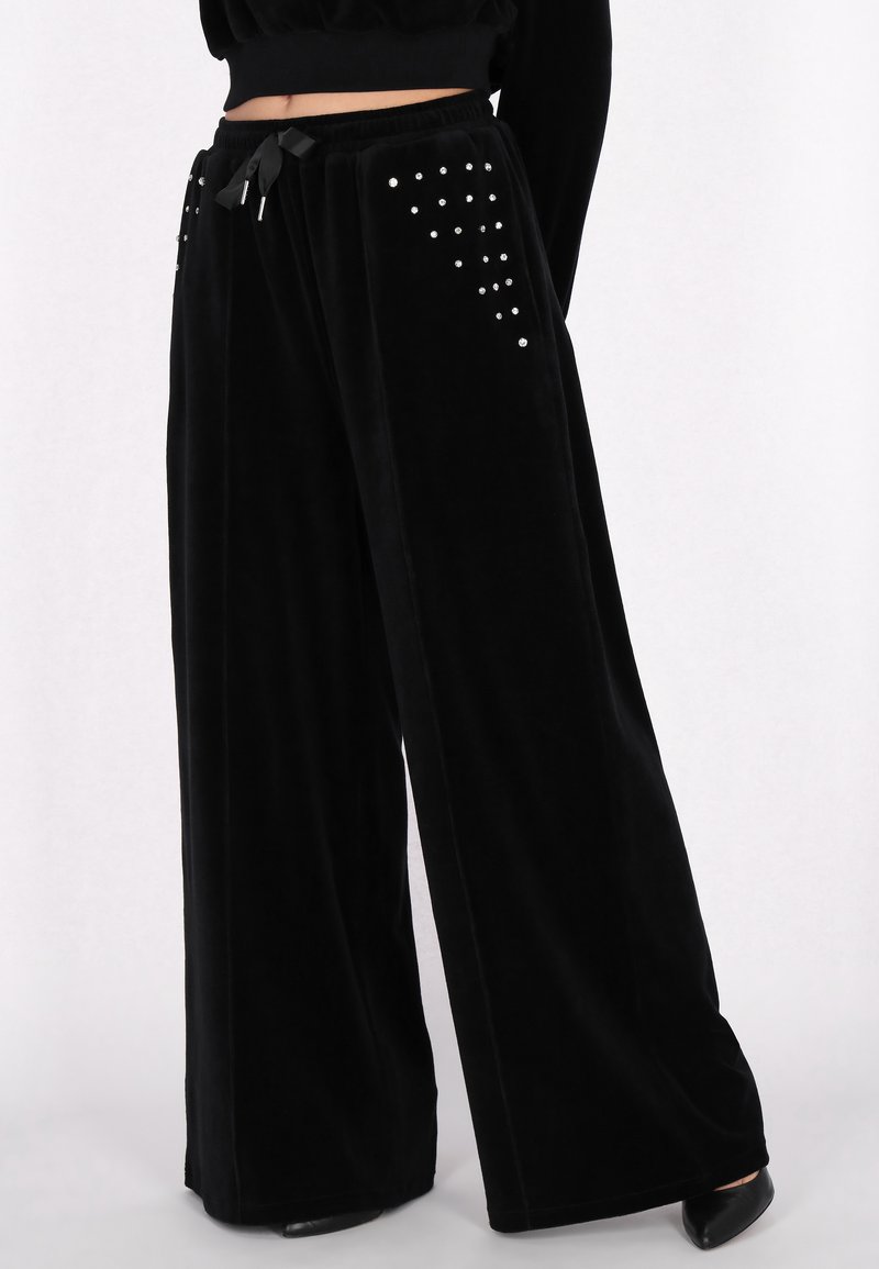 Czarne szyfonowe spodnie z szerokimi nogawkami, z elastycznym paskiem na sznurki oraz dekoracyjnymi srebrnymi ćwiekami ułożonymi w wzór na przednich kieszeniach.
