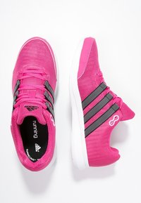 Zapatillas deportivas rosas con rayas negras, parte superior de malla, puntera redonda, cuello acolchado, con suela blanca y elementos de diseño texturizados.