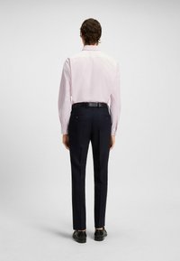 Lichtroze langesleeve shirt, donkerblauwe broek, zwarte leren schoenen, slank ontwerp en getailleerde pasvorm; minimalistische uitstraling zonder zichtbare patronen.