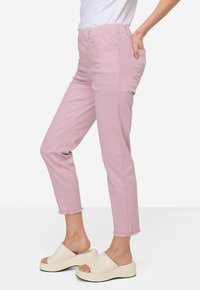 Pantaloni cropped elasticizzati color rosa chiaro con tasche laterali e design a gamba dritta, abbinati a sandali con zeppa color bianco sporco.