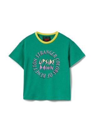 Zielony T-shirt z krótkim rękawem i żółtym kołnierzem, z okrągłym napisem "Stranger Colors of Benetton" otaczającym kolorowe geometryczne kształty na przodzie.