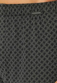 Zwarte stoffen shorts met een geometrisch wit patroon, voorzien van een elastische tailleband en een klein 'SCHIESSER' label vlakbij de bovenkant.