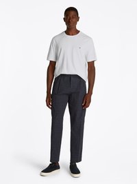 White cotton t-shirt with short sleeves, paired with navy pinstriped tailored trousers and dark navy shoes with white soles.