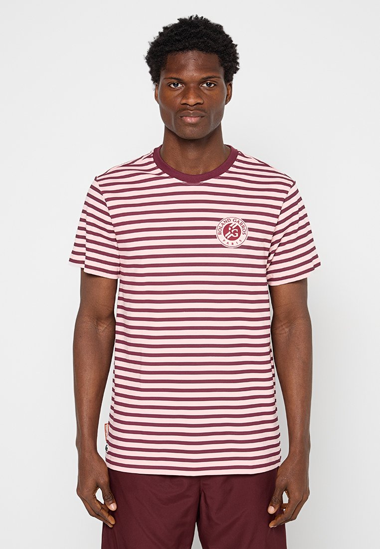 Camiseta de algodón a rayas color marrón y rosa claro con cuello redondo y un logo redondo en el área del pecho izquierdo. Manga corta, corte regular.