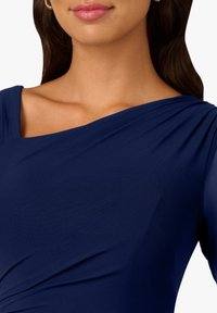 Granatowy, teksturowany top z tkaniny o asymetrycznym kroju z jednym ramieniem, z marszczeniem na całej długości i gładkim rękawem.