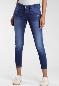 Mörkblå denimjeans med slim fit, med ljusa sömmar, framfickor och en liten logotypaccent nära midjebandet.