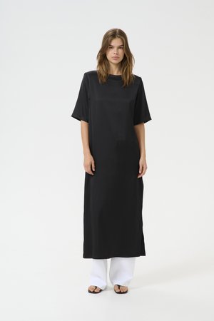 Zwarte midi-jurk met korte mouwen, met een rechte snit en een soepele textuur, gecombineerd met witte wijde broekspijpen en slippers.