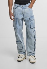 Lysblå denim cargo bukser med flere store sidelommer, en afslappet pasform og en falmet vask, parret med hvide sneakers.
