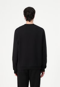 Czarny sweter z okrągłym dekoltem, długimi rękawami i ściągaczami. Gładki materiał, luźny krój i minimalistyczny design.