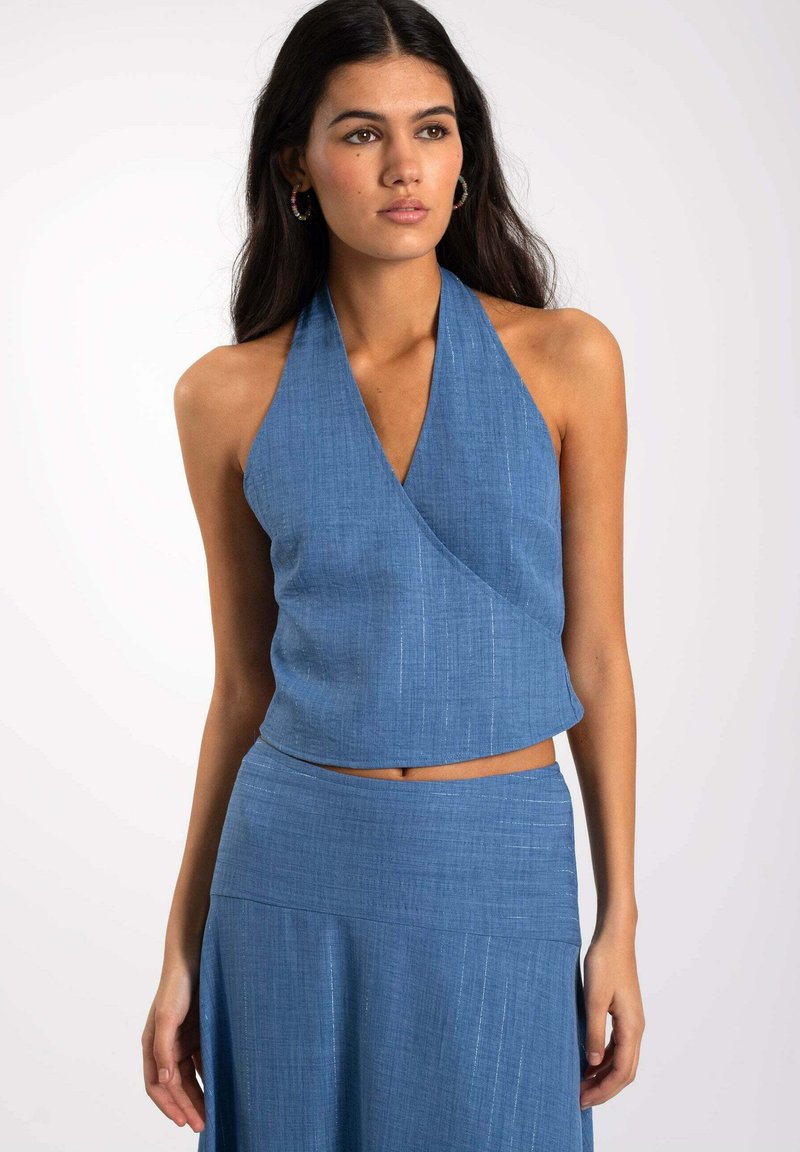 Top halter azul con tejido texturizado, diseño envolvente y longitud corta. Presenta un escote en forma de V y material suave y ligero.
