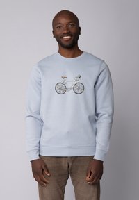 Hellblaues Sweatshirt mit einem Fahrradgrafik in Weiß und Grau, ergänzt durch braune Akzente sowie gerippte Bündchen und Saum.