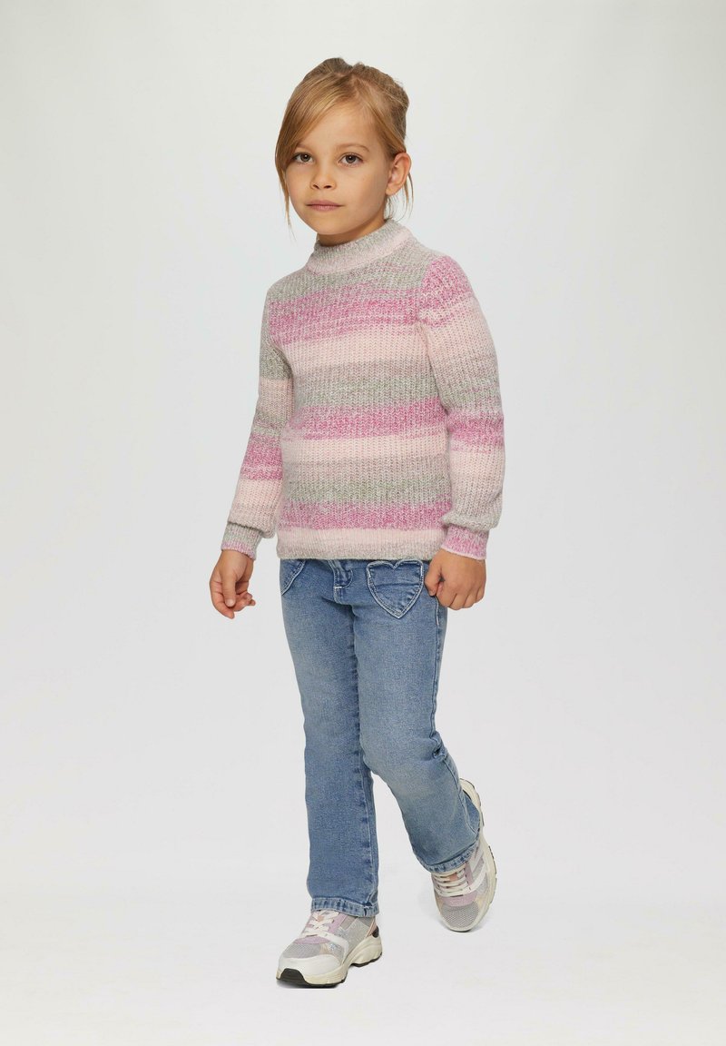 Pull en tricot avec des rayures roses, grises et blanches ; col montant ; associé à un jean bleu ; portant des baskets grises et blanches. Enfant marchant vers l'avant.